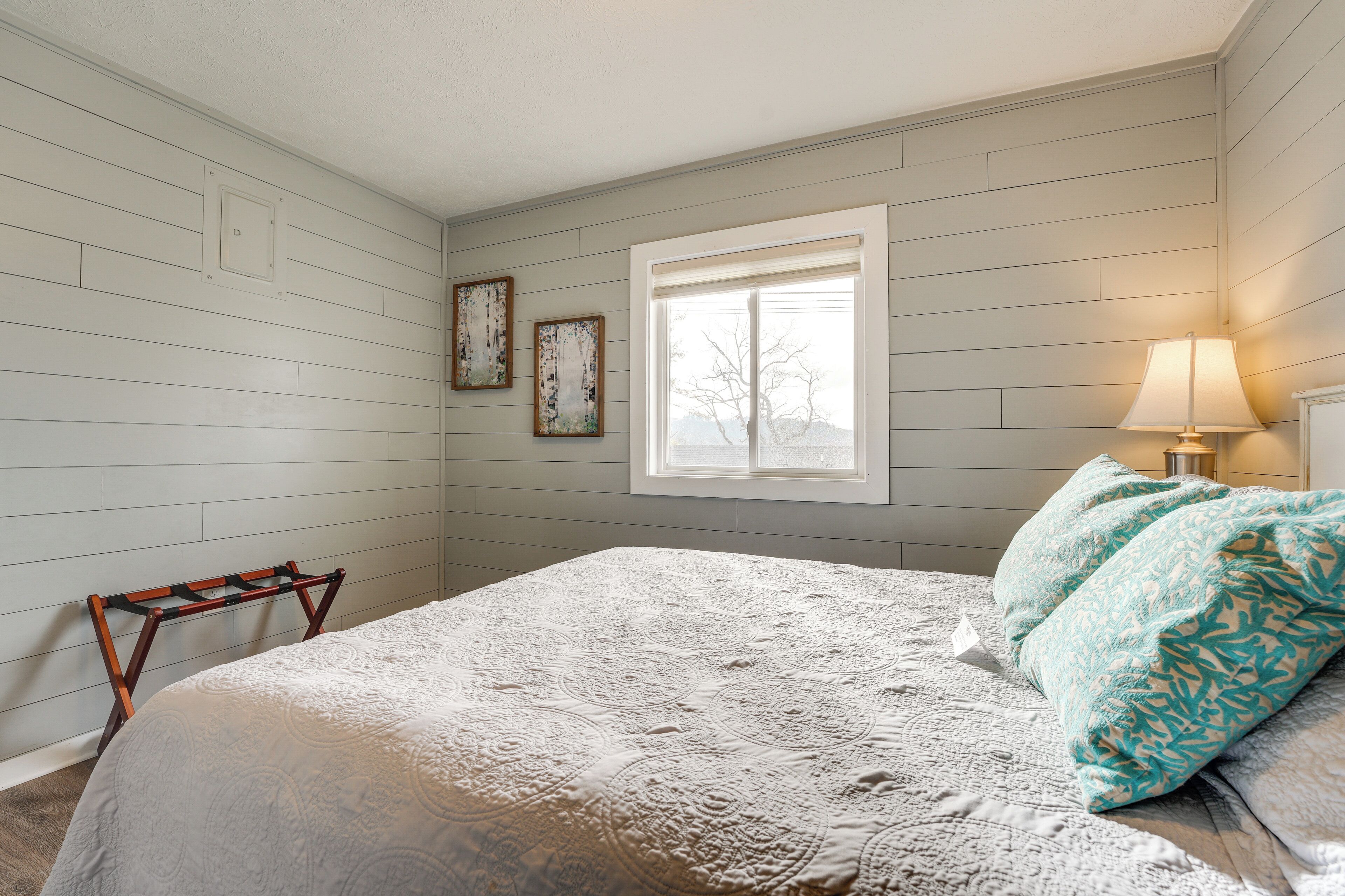 Ein Schlafzimmer mit Bett, Fenster, Wandregal und Lampe.