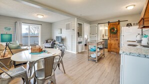 A spacious living area with a dining table, chairs, and a kitchen area with a refrigerator and sink. - Lake & Trail Access: Cape Fair Cottage w/ Deck (Cape Fair)