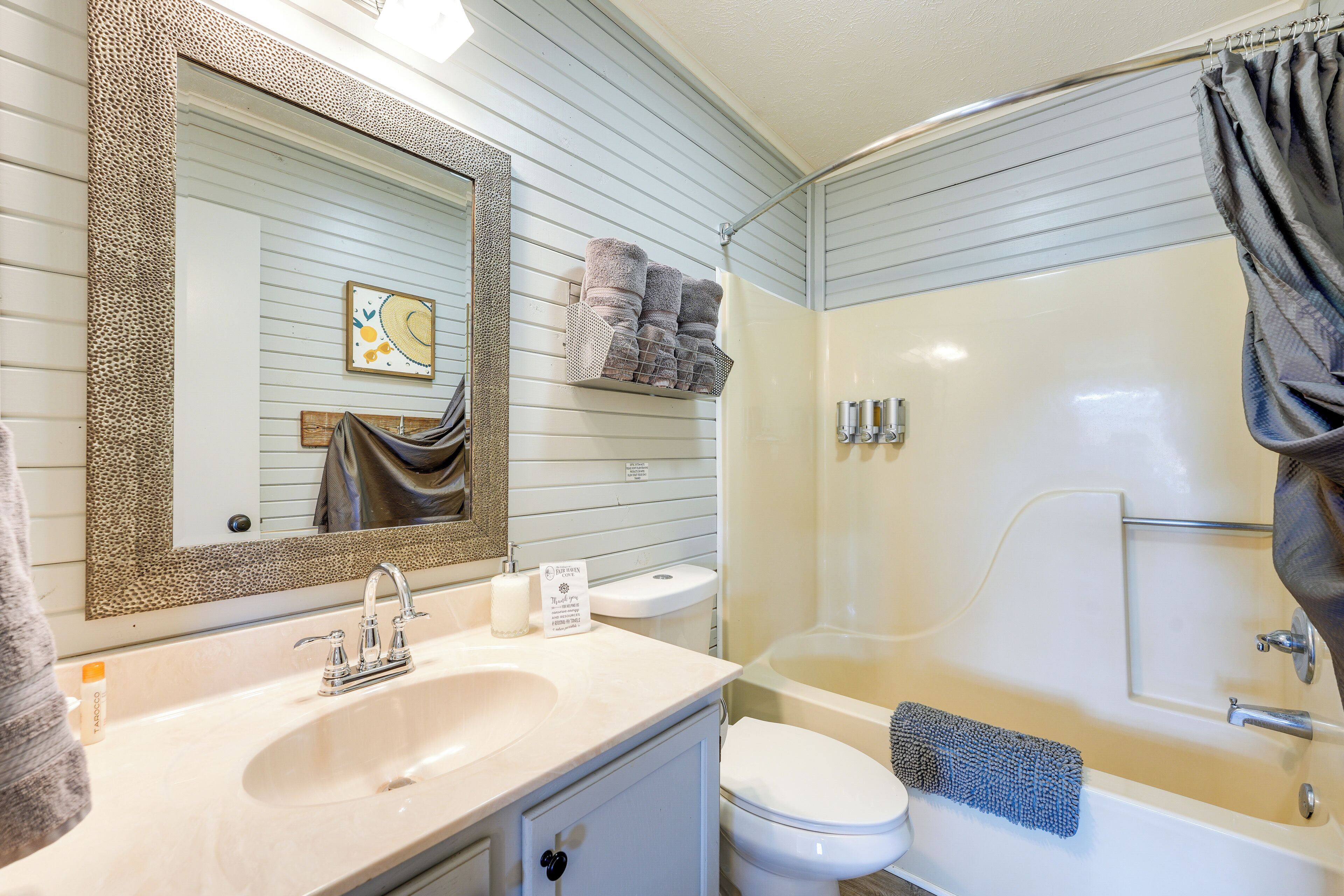 A bathroom with a sink, toilet, and bathtub. There are towels and toiletries visible.