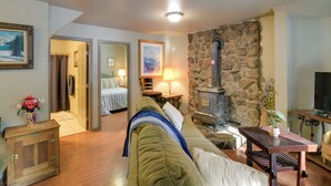 A cozy living room with a stone fireplace, a sofa, a wooden cabinet, and a television.
