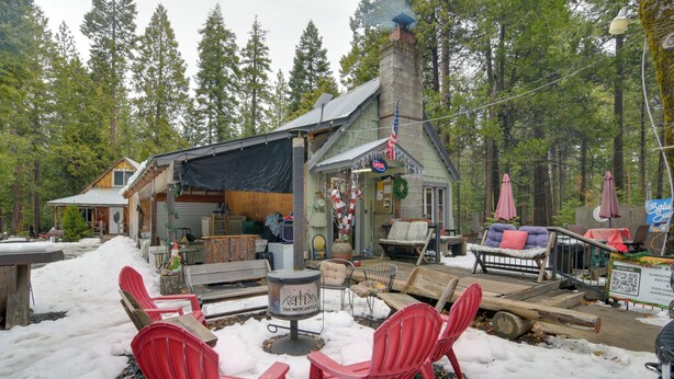 A cozy cabin with a fireplace, outdoor seating, and a snow-covered deck.