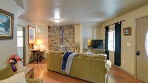 A living room with a stone wall, a sofa, a television, and a dining area with a table and chairs.