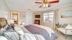 A bedroom with a bed, a ceiling fan, a window with curtains, a TV, a chair, and a plant. - Tulsa Home 5 Mi to Downtown: Groups Welcome! (Tulsa)