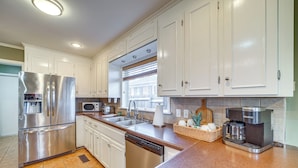 A modern kitchen with white cabinets, stainless steel appliances, and a granite countertop. - Tulsa Home 5 Mi to Downtown: Groups Welcome! (Tulsa)