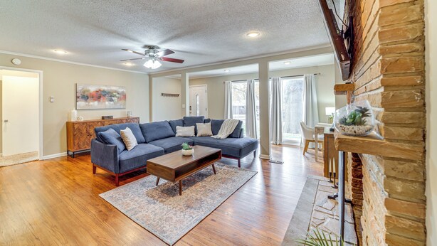 A spacious living room with hardwood flooring, a dark blue sectional sofa, a wooden coffee table, and a ceiling fan. - Tulsa Home 5 Mi to Downtown: Groups Welcome! (Tulsa)