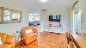 A spacious living room with hardwood flooring, a leather sofa, a coffee table, and a TV mounted on the wall. - Tulsa Home 5 Mi to Downtown: Groups Welcome! (Tulsa)