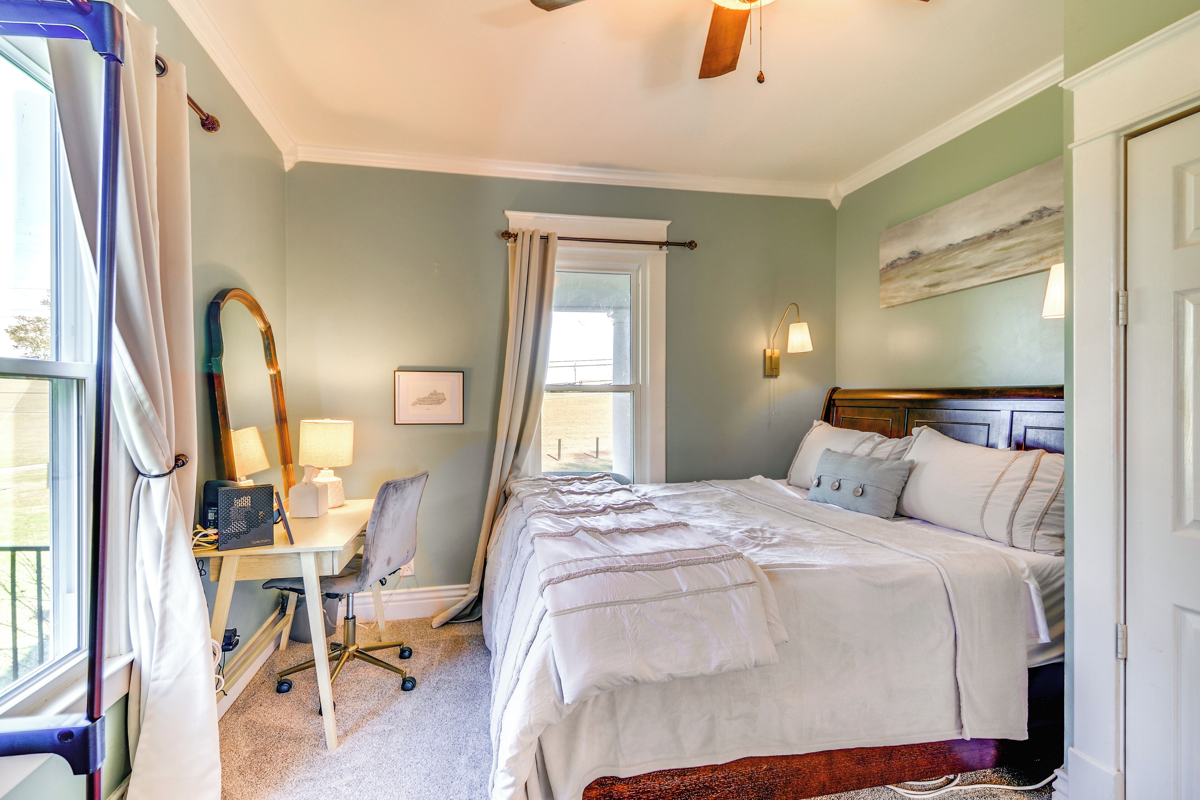 A bedroom with a bed, desk, chair, and a window with curtains.