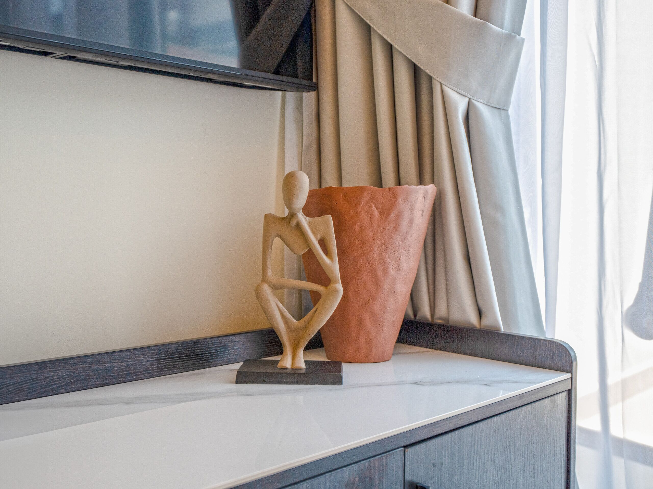 Strak interieur met een sculptuur en een terracotta pot op een marmeren oppervlak.