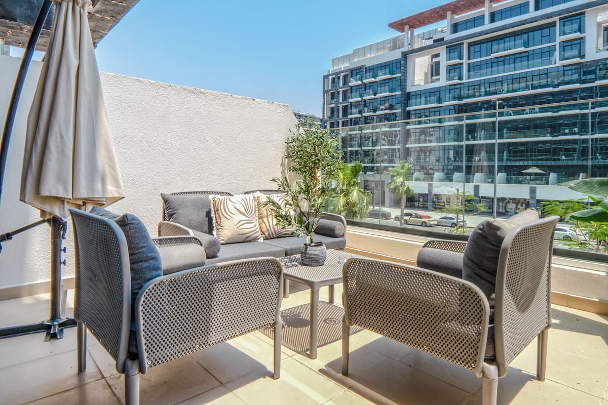 A balcony with wicker furniture, a table, and a potted plant.