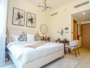 A modern hotel room with a large bed, a desk, a chair, and artwork on the walls. - Easygo-spacious Luxury STU Azizi Rivra16 (Dubai)