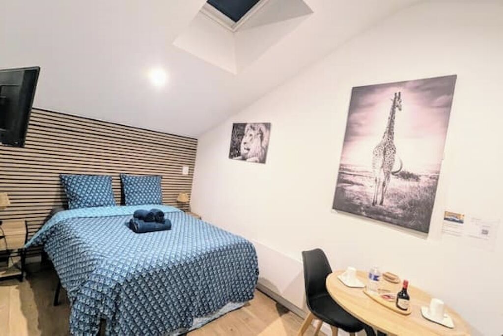 Une chambre avec un lit, un bureau et une chaise. Il y a deux tableaux accrochés au mur.