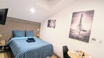 Une chambre avec un lit, un bureau et une chaise. Il y a deux tableaux accrochés au mur.