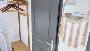 A room with a grey door, a wooden bench, a wall-mounted mirror with macrame tassels, and a clothes drying rack. - Studio 5: Your urban oasis.  (Gond-Pontouvre)