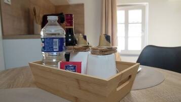 Un plateau en bois avec une bouteille d’eau, une bouteille de vin, un morceau de fromage et un paquet de collations, le tout posé sur une table.