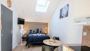 A compact room with a bed, a small dining table, a chair, a TV, and a skylight. - Studio 5: Your urban oasis.  (Gond-Pontouvre)