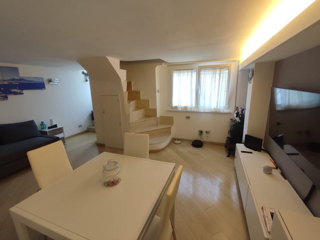 Ein modernes Wohnzimmer mit Treppe, Essbereich und Fernseher.