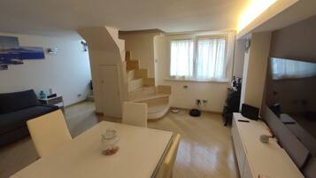 Ein modernes Wohnzimmer mit Treppe, Essbereich und Fernseher.
