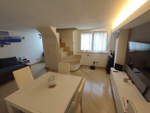 Una sala de estar moderna con una escalera, un comedor y un televisor.