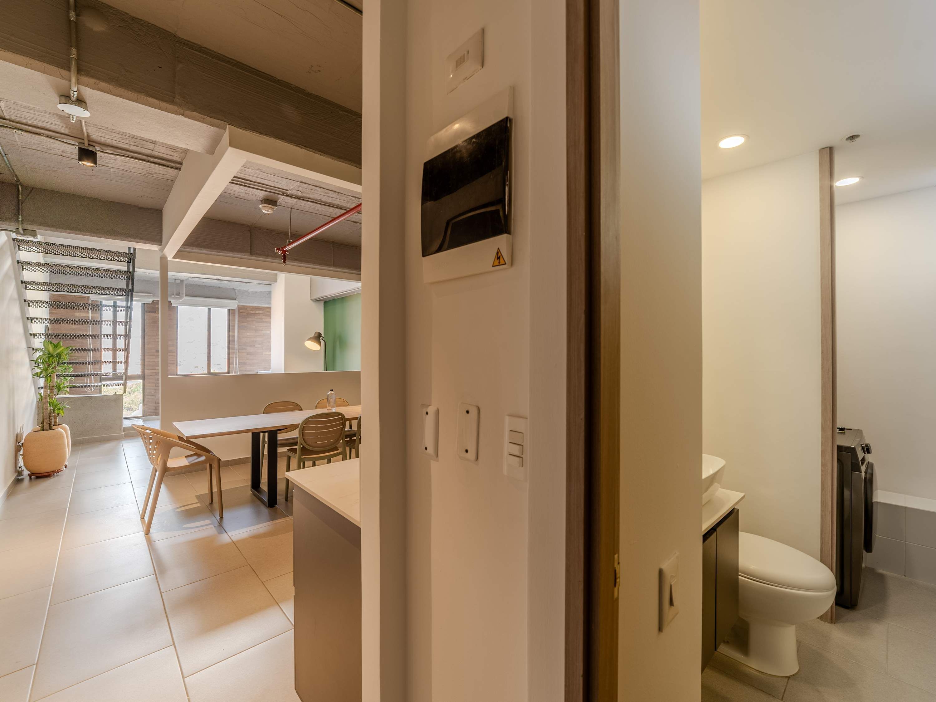 A modern interior with a dining area, a kitchenette, and a bathroom.