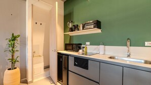 A modern kitchen with stainless steel appliances, a green accent wall, and a potted plant. - W Contemporary Loft w AC in Trendy Laureles (Medellín)