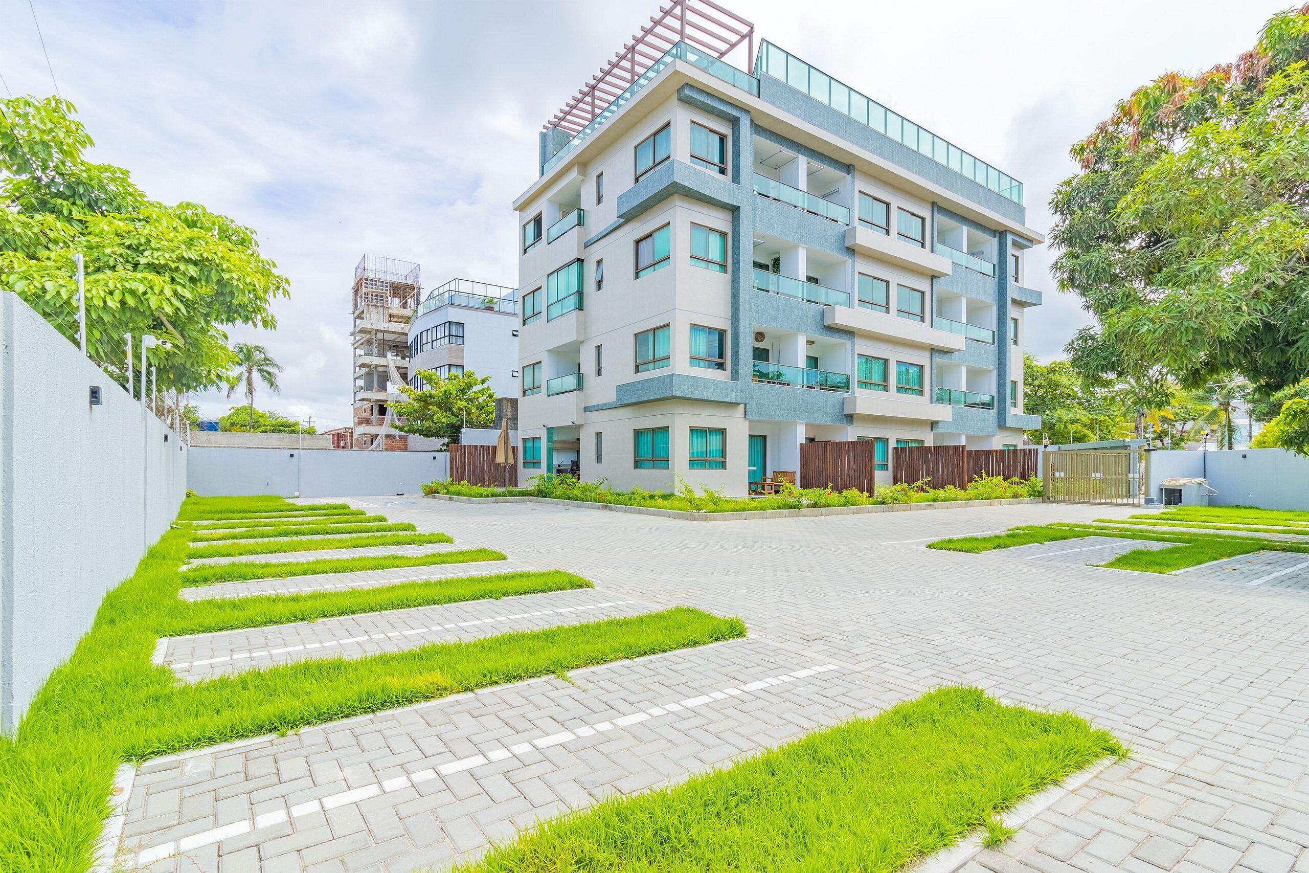 A modern multi-story residential building with a flat roof, large windows, and a balcony on the upper floors.