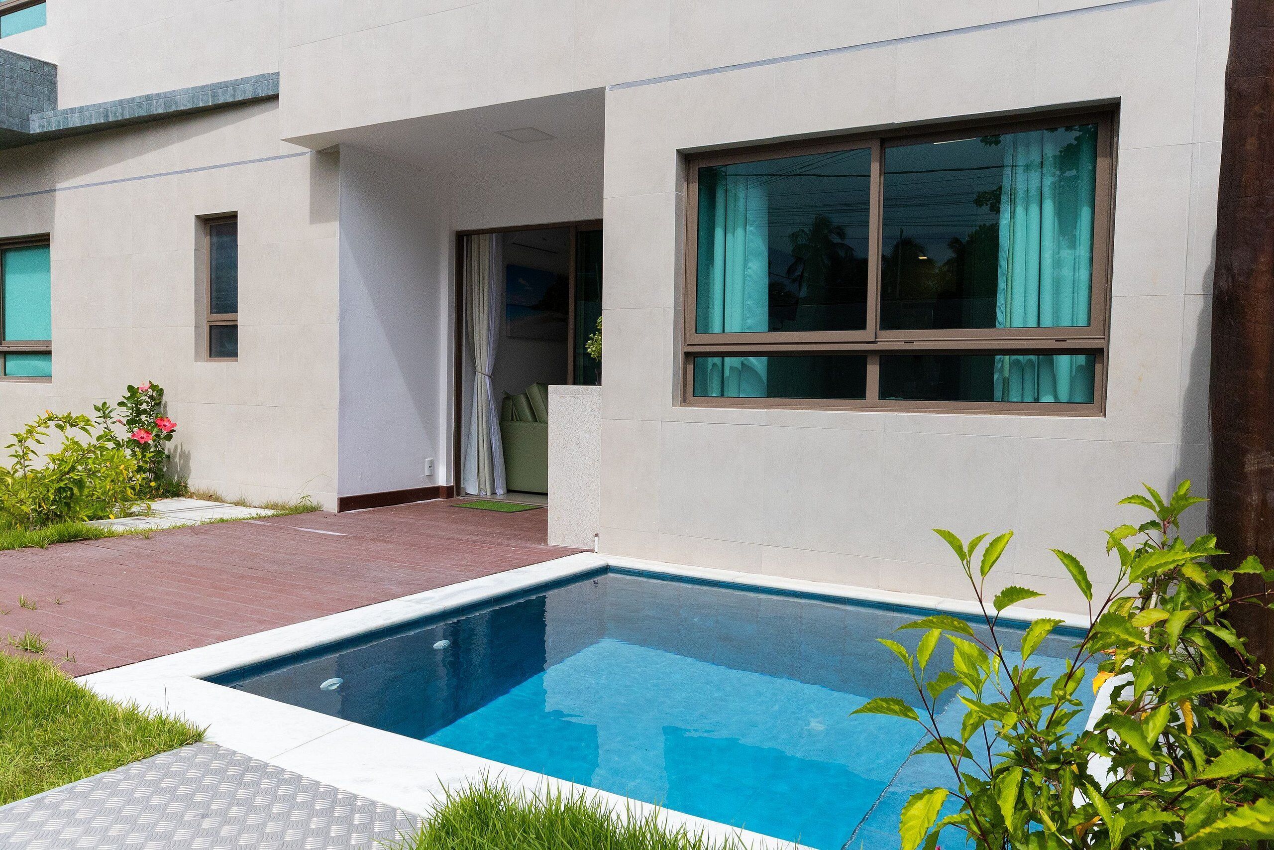 Una casa moderna con piscina, patio e un'ampia finestra.