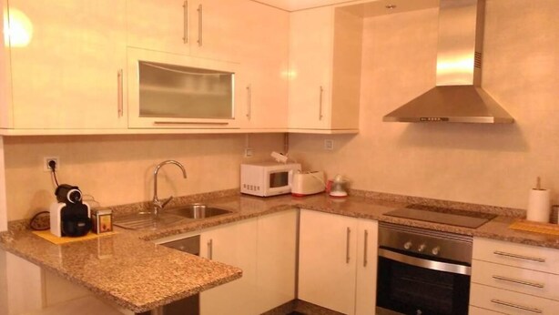 A compact kitchen with a microwave, oven, and stainless steel sink. - Modern apartment on the Fisterra Road (Negreira)