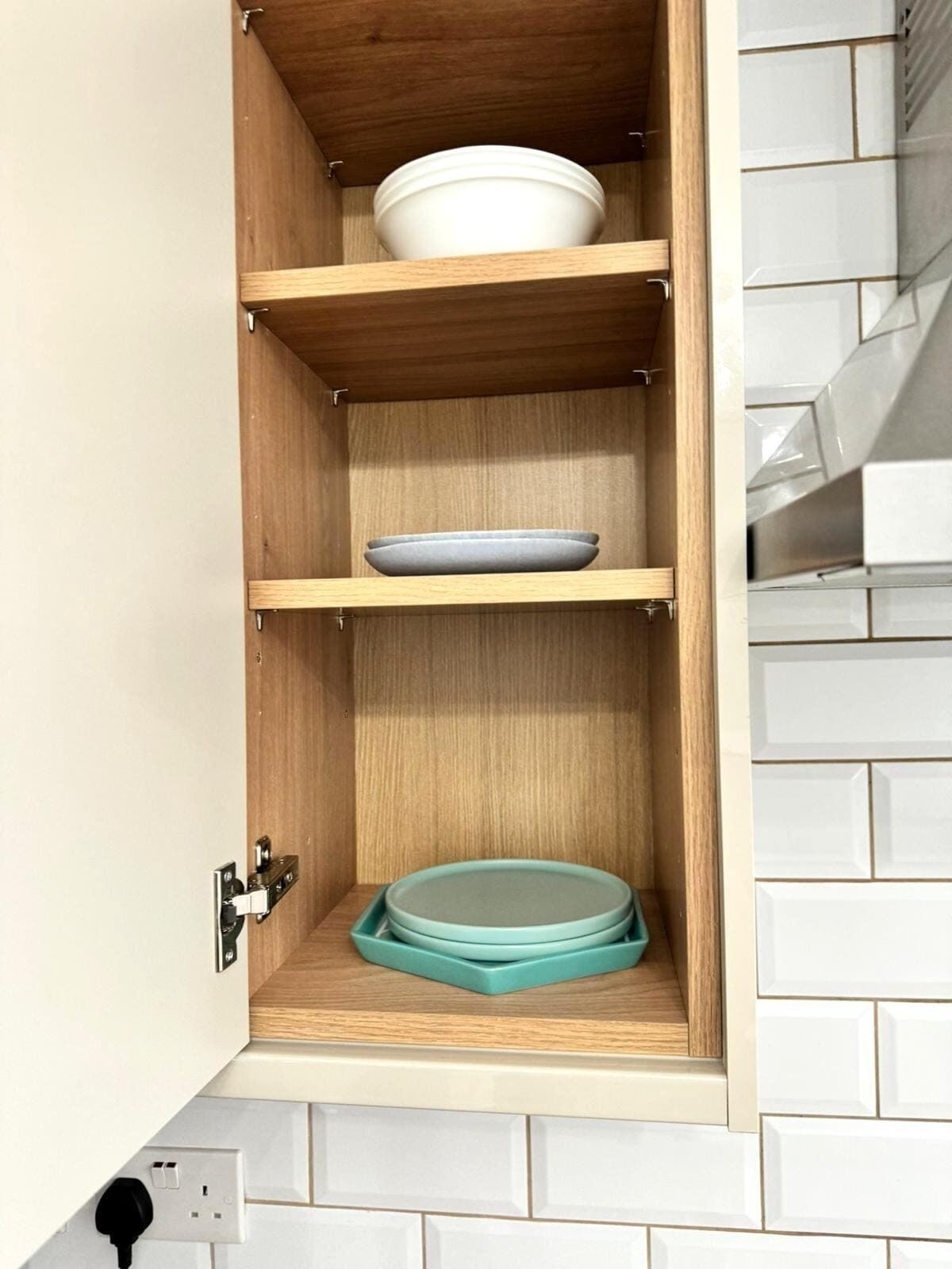 A kitchen cabinet with three shelves, each holding a dish.