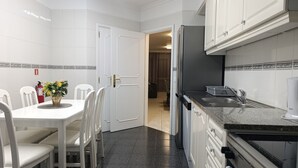 A kitchen with white cabinets, a granite countertop, and a dining area with white chairs and a table. - Sea View Forum Wi-Fi, AC & Parking 1 minute from Forum Madeira (Funchal)