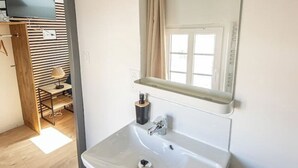 A bathroom with a white sink, a mirror, and a window. - Studio 4 - Bright Cocoon  (Gond-Pontouvre)