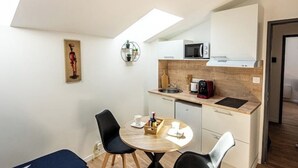 A compact kitchen with a microwave, sink, and a small dining area with two chairs and a table. - Studio 4 - Bright Cocoon  (Gond-Pontouvre)