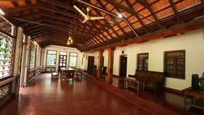 A spacious hall with wooden beams, a ceiling fan, and traditional wooden furniture.