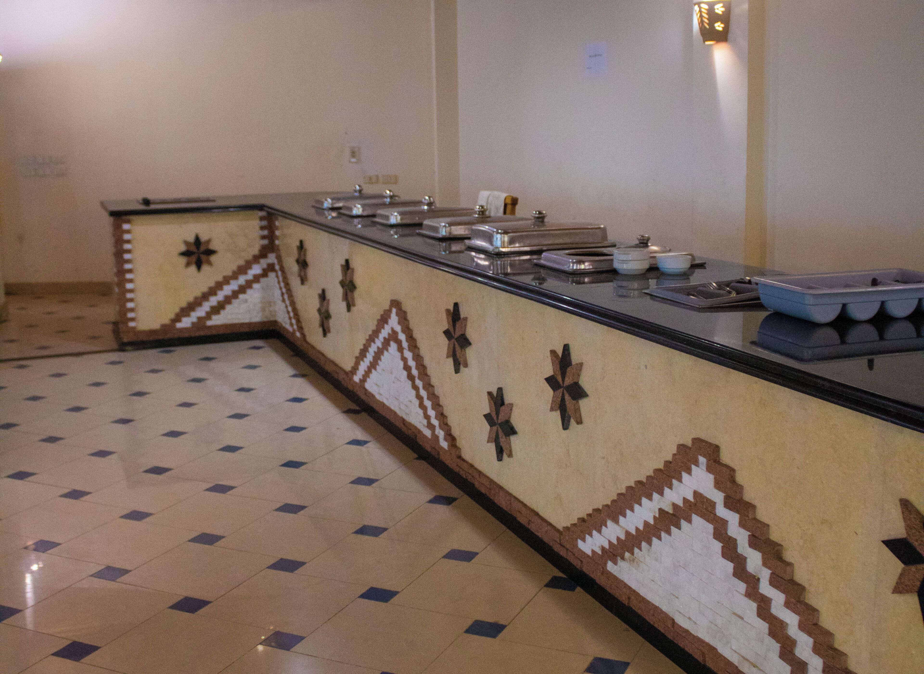 A long counter with a patterned design, a tiled floor, and a wall-mounted light fixture.