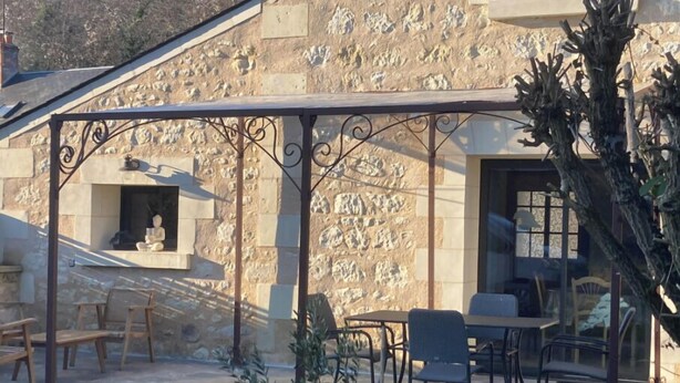 A stone building with a covered patio area featuring outdoor seating and a statue.