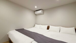 Un dormitorio con cama, paredes blancas y aire acondicionado instalado en el techo.