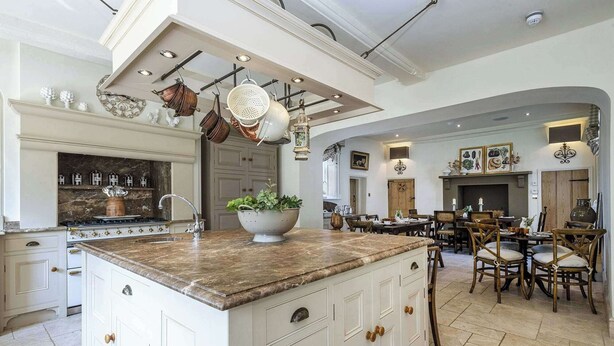 A spacious kitchen with a large island, white cabinetry, and a dining area with wooden chairs and a table. - Ormesby Manor - 8 Beds - Sleeps 16 - Hot Tub (Great Yarmouth)