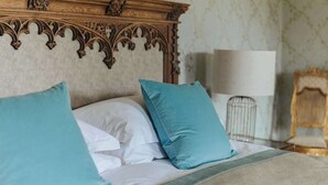 A bed with a wooden headboard, white and teal pillows, and a beige bedspread. - Ormesby Manor - 8 Beds - Sleeps 16 - Hot Tub (Great Yarmouth)