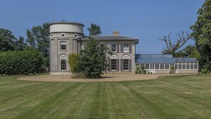 A large, historic stone building with a round tower, multiple windows, and a conservatory. - Ormesby Manor - 8 Beds - Sleeps 16 - Hot Tub (Great Yarmouth)
