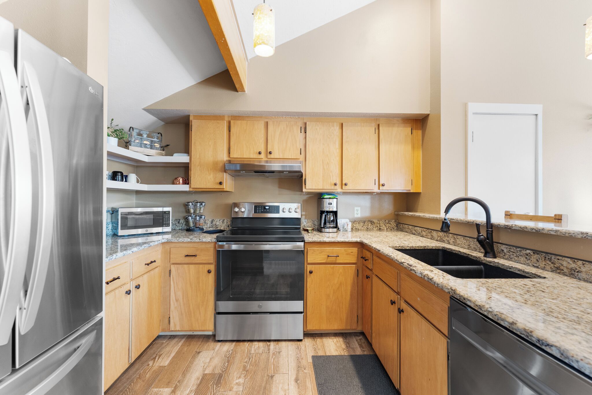 Eine moderne Küche mit Holzausstattung, Edelstahlgeräten, Granitarbeitsplatten und einem eingebauten Backofen.