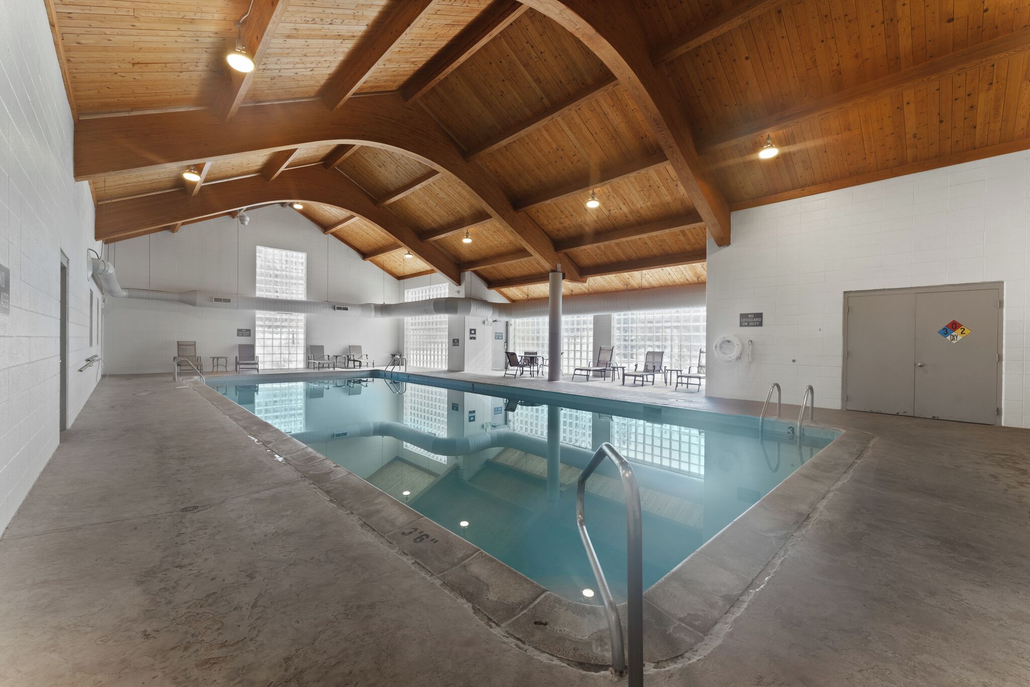 Ein Innenpool mit Holzbalkendecke und großen Glaswänden.