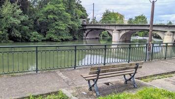 Un banc al costat d'un riu amb un pont al fons.