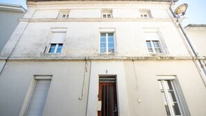 A building with a central entrance, two windows on the upper floor, and a satellite dish on the roof. - Studio 3 - Cocon Douillet : Le Confort  (Gond-Pontouvre)
