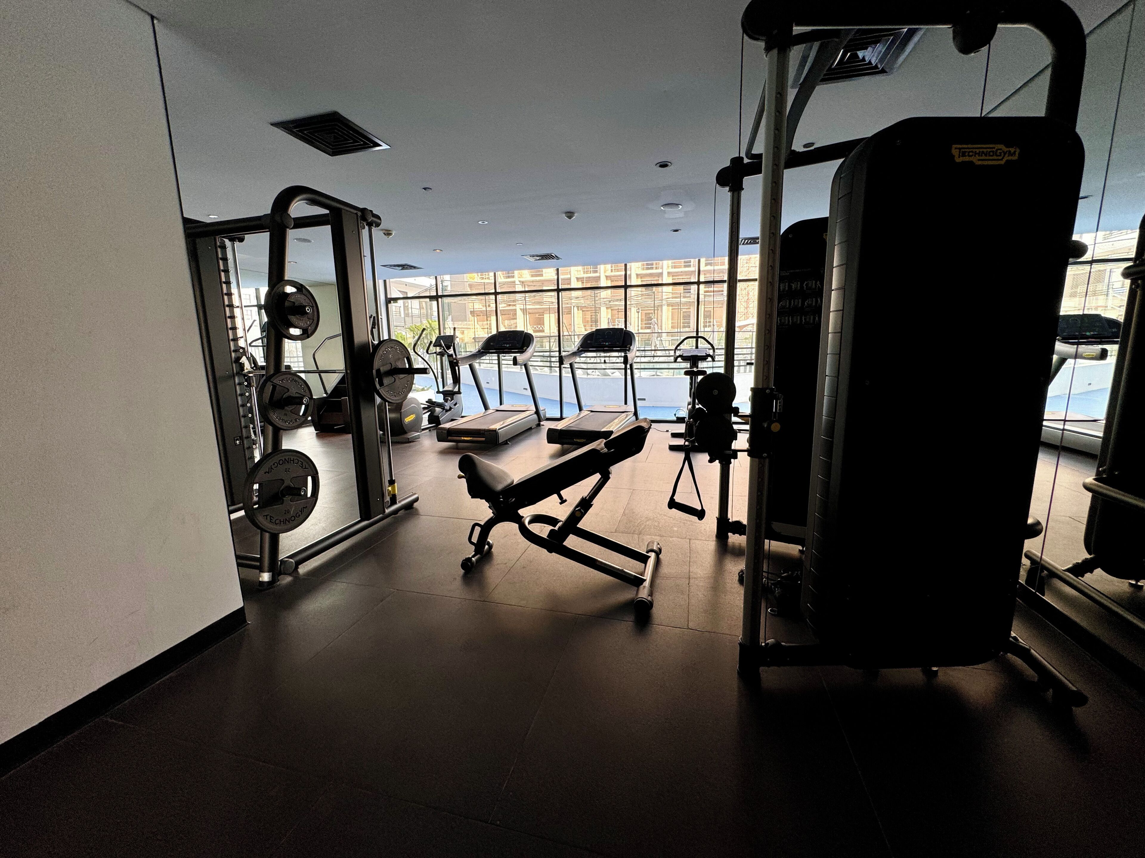 Ein Fitnessstudio mit unterschiedlicher Trainingsausstattung, darunter Laufbänder, Kraftgeräte und Kurzhanteln.
