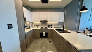 A modern kitchen with a marble floor, stainless steel appliances, and a sleek design. - Easygo-upgraded 1bdr Mageye MBR (Dubai)