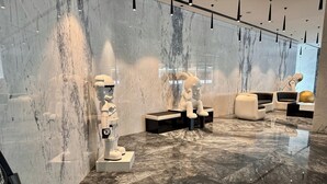 A modern interior with marble walls and floors, featuring a robot figure and contemporary seating. - Easygo-upgraded 1bdr Mageye MBR (Dubai)