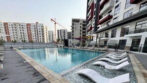 A swimming pool with lounge chairs and a tiled deck. - Easygo-upgraded 1bdr Mageye MBR (Dubai)