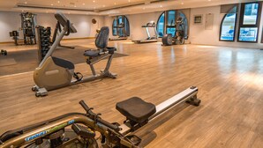 A spacious gym with various exercise equipment, large windows, and a wooden floor. - Easygo- Spaciou STU With Pool Viewlp17 (Dubai)