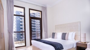 A hotel room with a large bed, a nightstand, a chair, and a view of a building through the windows. - Easygo- Spaciou STU With Pool Viewlp17 (Dubai)