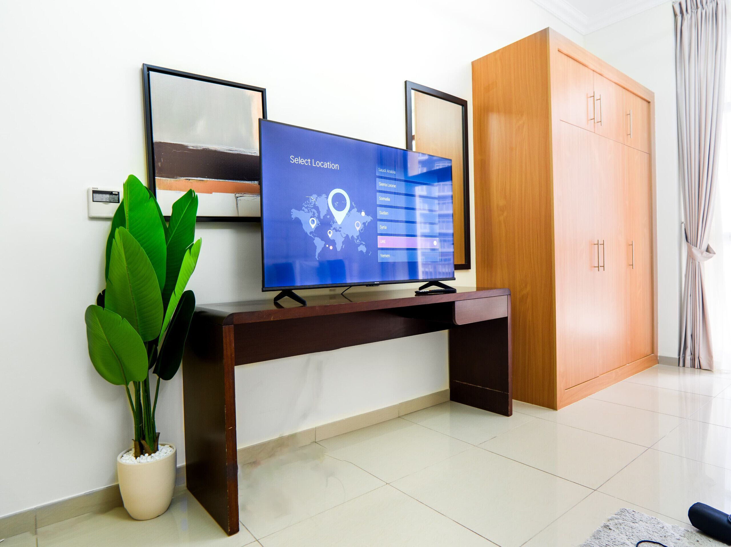 A modern room with a flat-screen TV on a wooden console table, a potted plant, and a wardrobe.