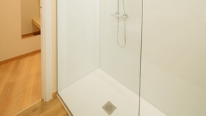 A modern bathroom with a glass shower enclosure, a visible showerhead, and a wooden floor. - Mouritz Rooms triple in Negreira (Negreira)